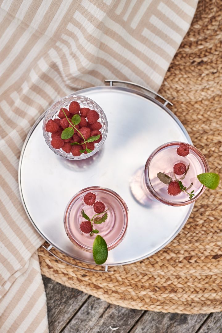 Et praktisk brett er et bra shoppingtips for sommeren slik at du enkelt kan servere drinker eller desserter på det. Her et brett i stål fra Stelton med rosa drinker på. 