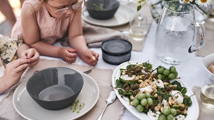 Små fingre strekker seg etter nøttene i den friske sommersalaten med geitost.