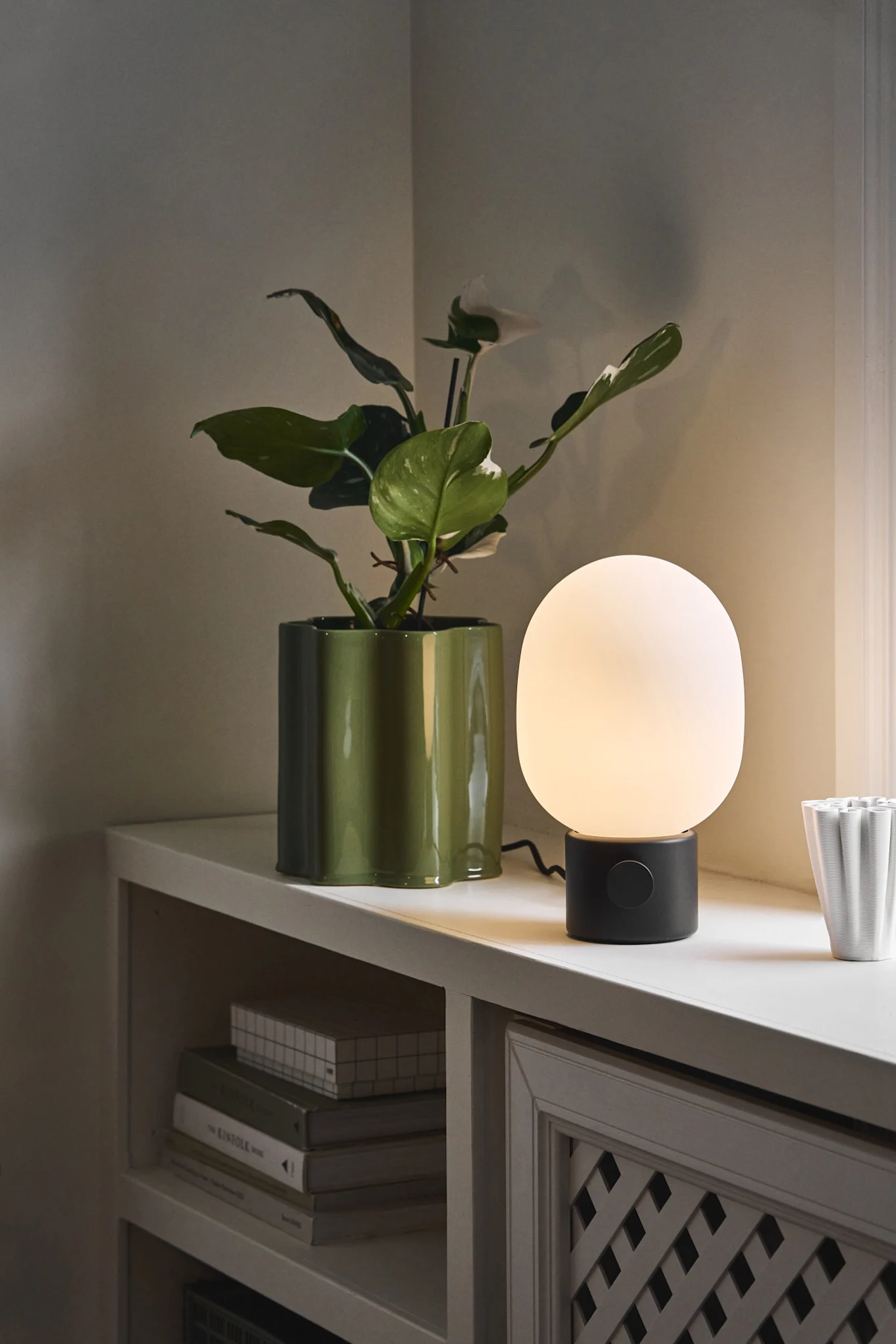 Designlamper: JWDA-bordlampen fra Audo Copenhagen står ved siden av en blomsterpotte på en vinduskarm.