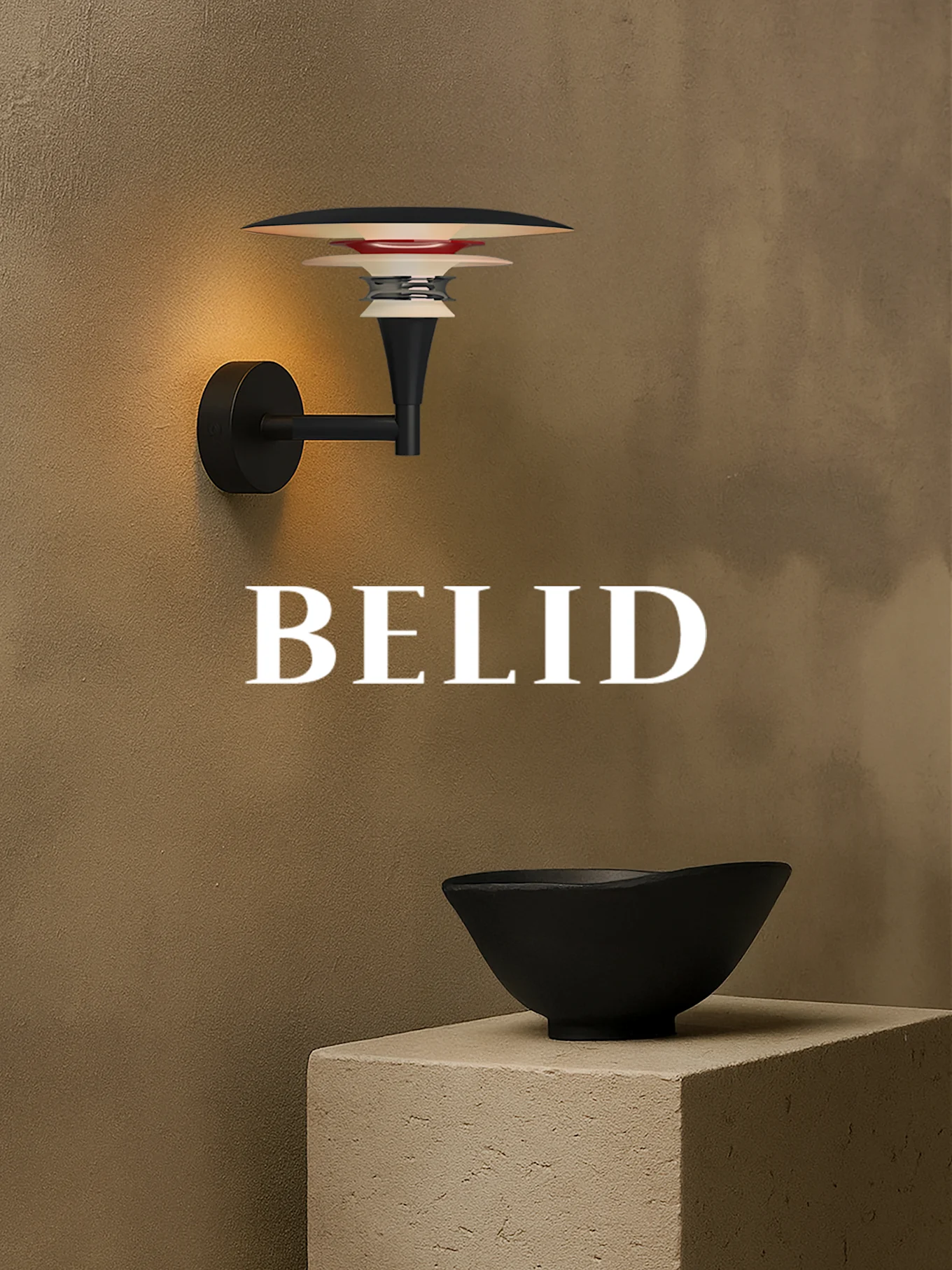 Vegghengt lampe med lagdelte skjermer lyser opp teksturert brun vegg. Svart bolle på betongblokk. 'BELID' tekst.