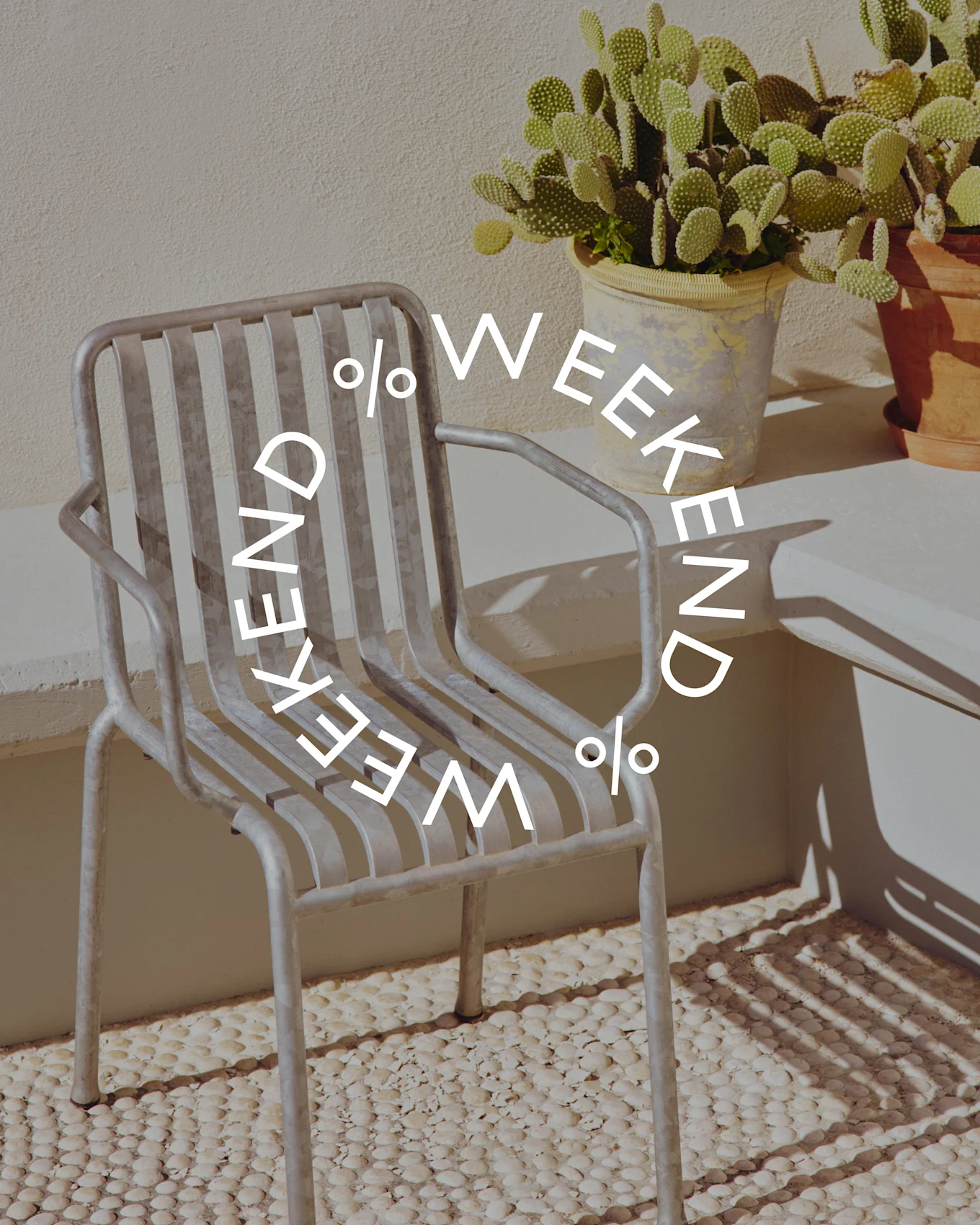 Grå stol med metallspiler ved en potteplante-kaktus, med sirkulær tekst 'WEEKEND % WEEKEND %'.