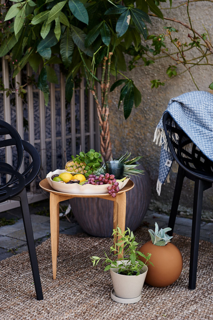 Et tips for å innrede en uteplass i middelhavsstil er med mindre trebord, krukker og et fint fat på bordet fullt av frukt som på bildet.