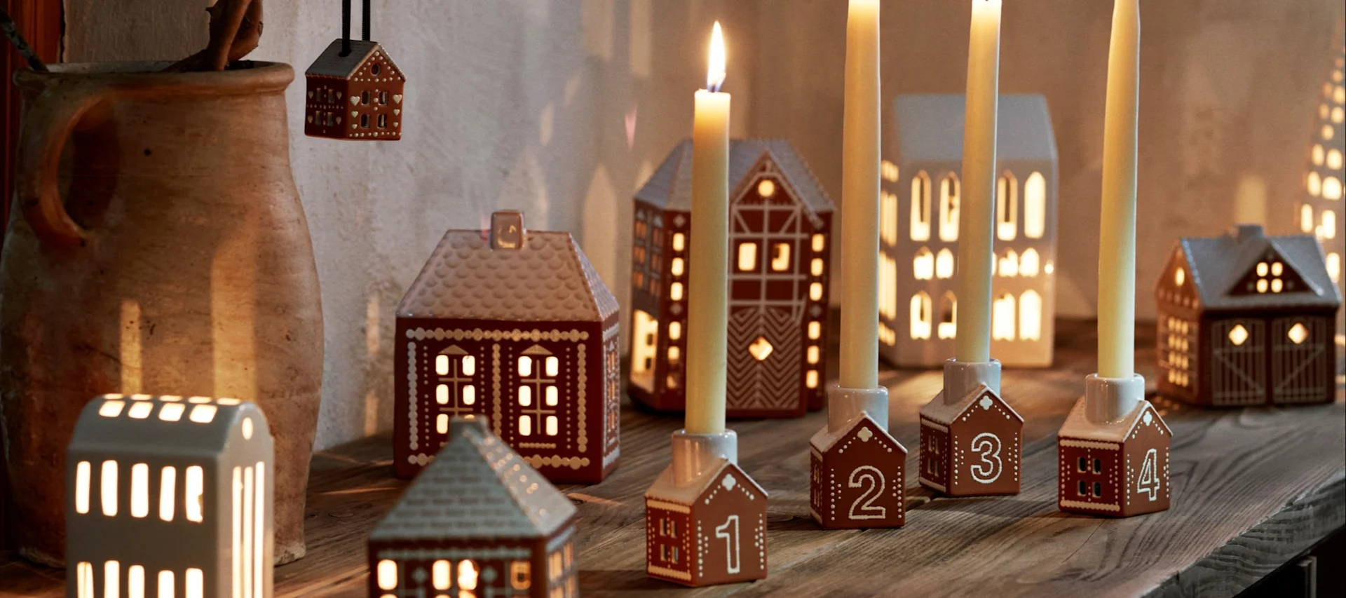 Klassiske julefavoritter - her ser du en gutt som spiser pepperkaker ved siden av lysestaker i pepperkakehusform.