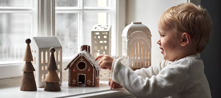 Klassiske julefavoritter - her ser du en gutt som spiser pepperkaker ved siden av lysestaker i pepperkakehusform.