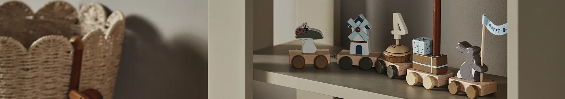 Et treleketog på en hylle, med vogner som viser en marihøne, vindmølle, cupcake med "4"-lys, gave og en kanin med "Happy B"-flagg.