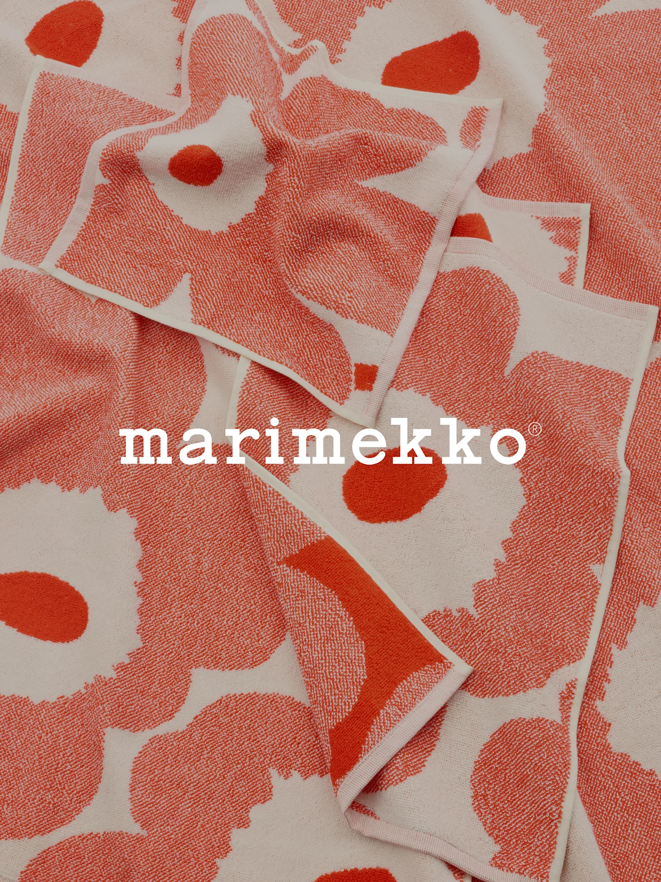 Brettede korallfargede og eggehvite mønstrede håndklær med Marimekko-logo.