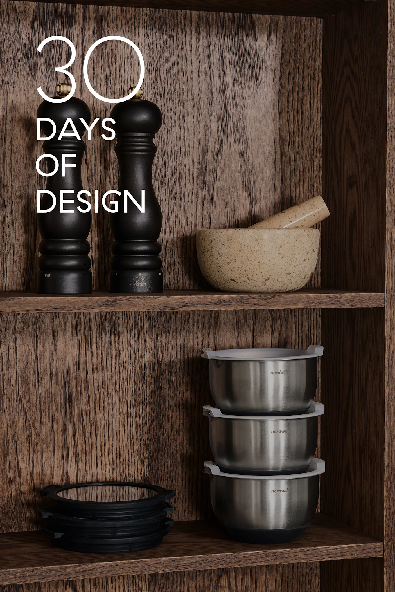 Trehyller med kjøkkenutstyr: svarte kverner, morter & støter, stålboller, silikonringer. Tekst: 30 DAYS OF DESIGN.