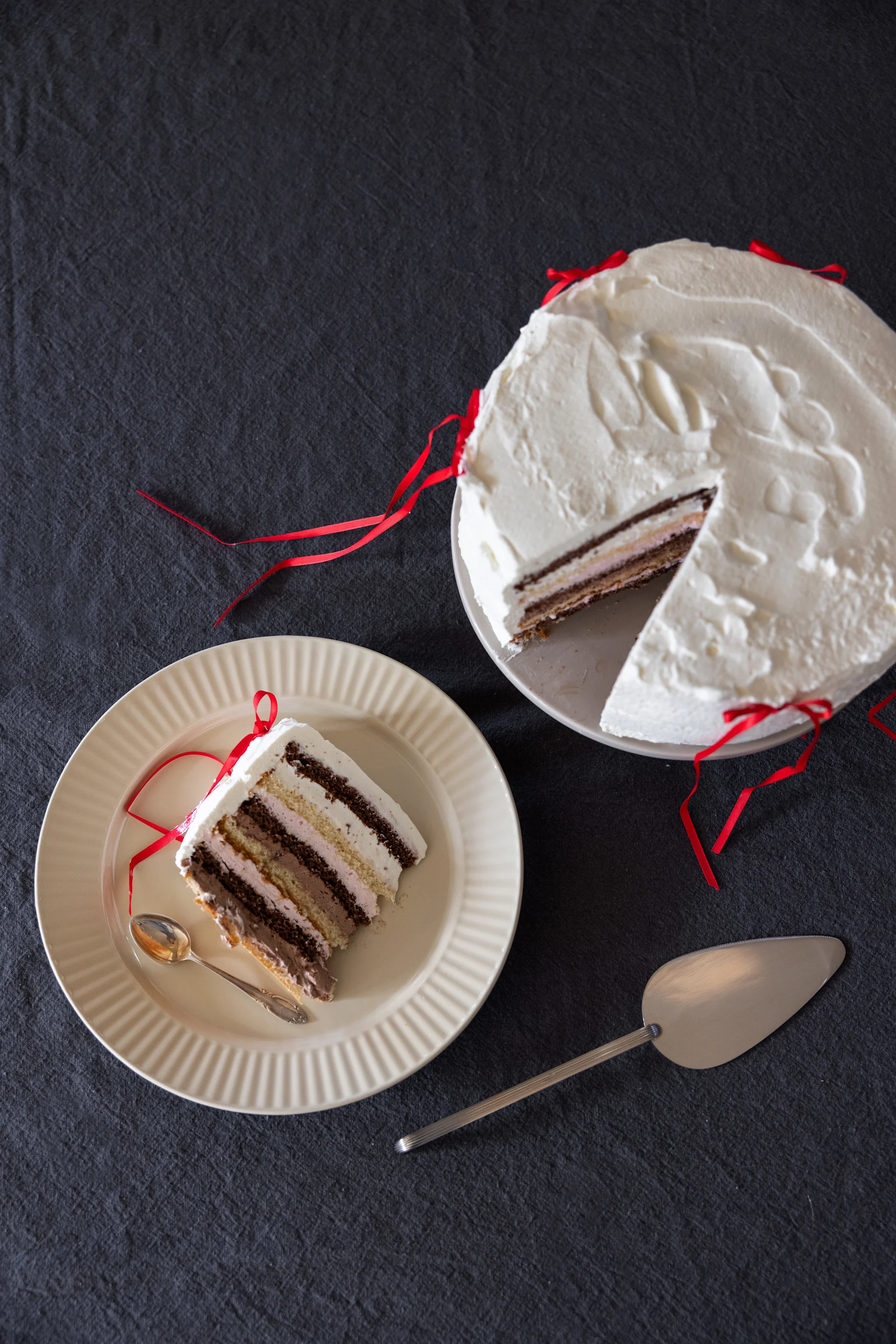 En bløtkake på et fat, ved siden av et kakestykke på et annet fat fra Sagaforms Coffee & More-kolleksjon i beige.