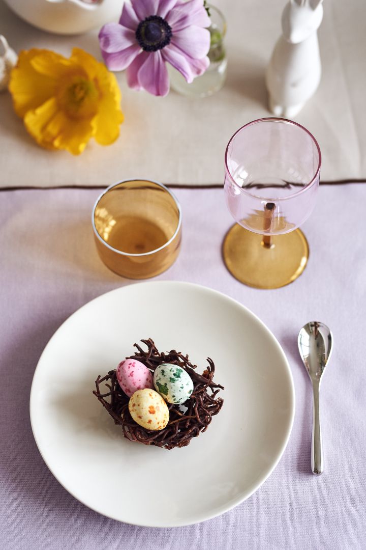 Lag et festlig påskebord i vårlige pasteller med deilige sjokoladefuglereir på en Arabia-tallerken sammen med Tint-glass og vinglass fra HAY.