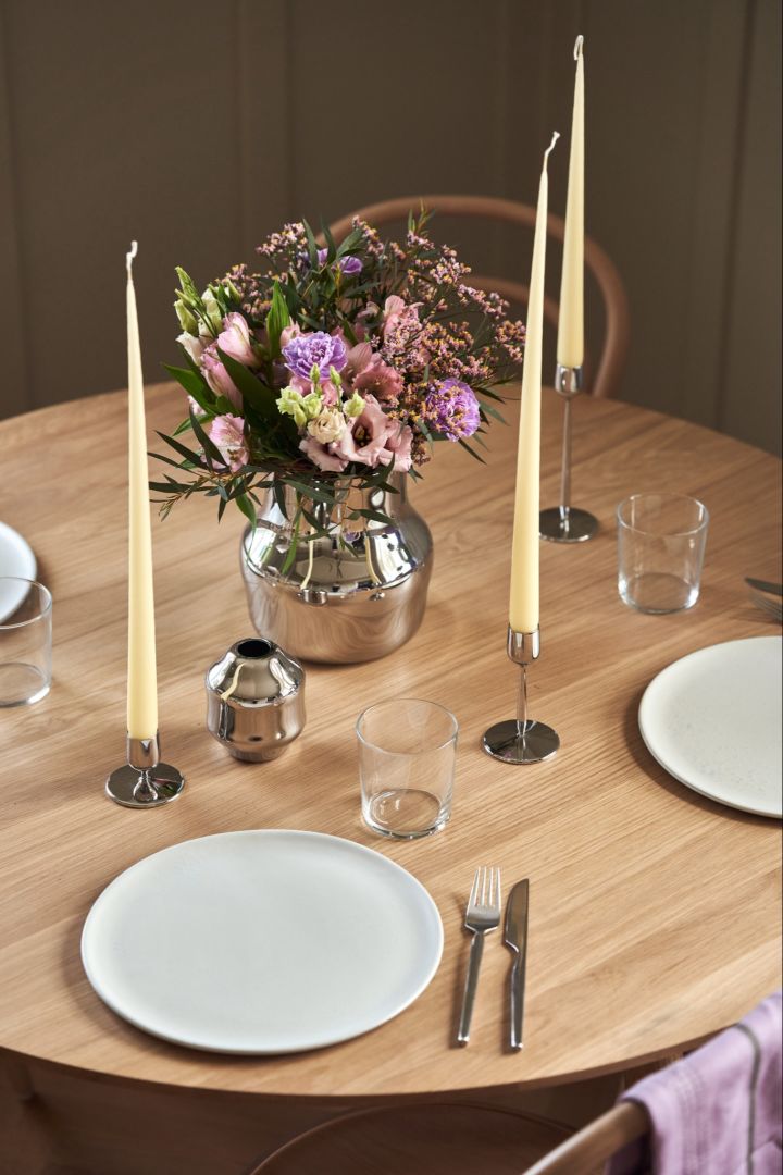 En elegant borddekning med en polert vase i rustfritt stål fra Dorotea-serien fra Gense og matchende lysestaker.