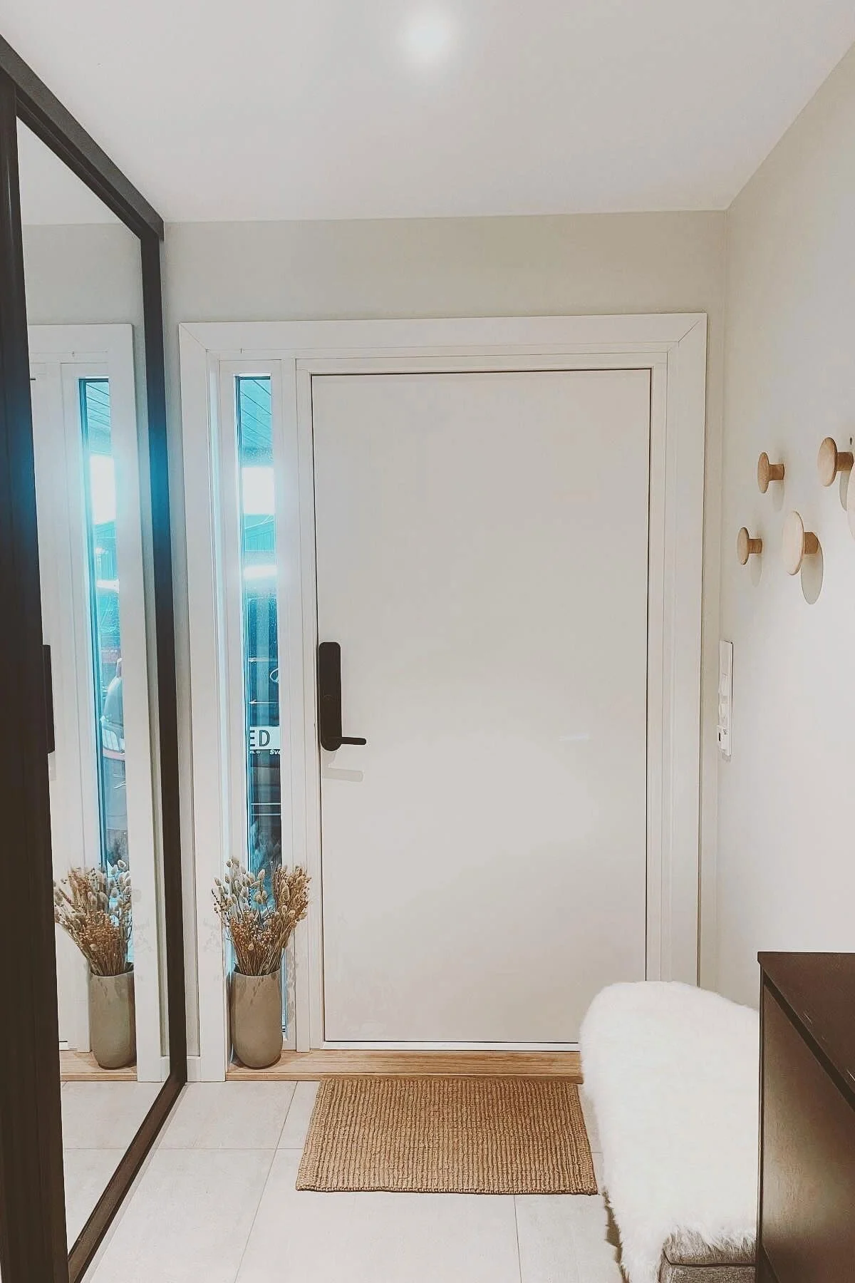 En entré i skandinavisk stil med et speil, en inngangsdør og Dots veggknagger fra Muuto.
