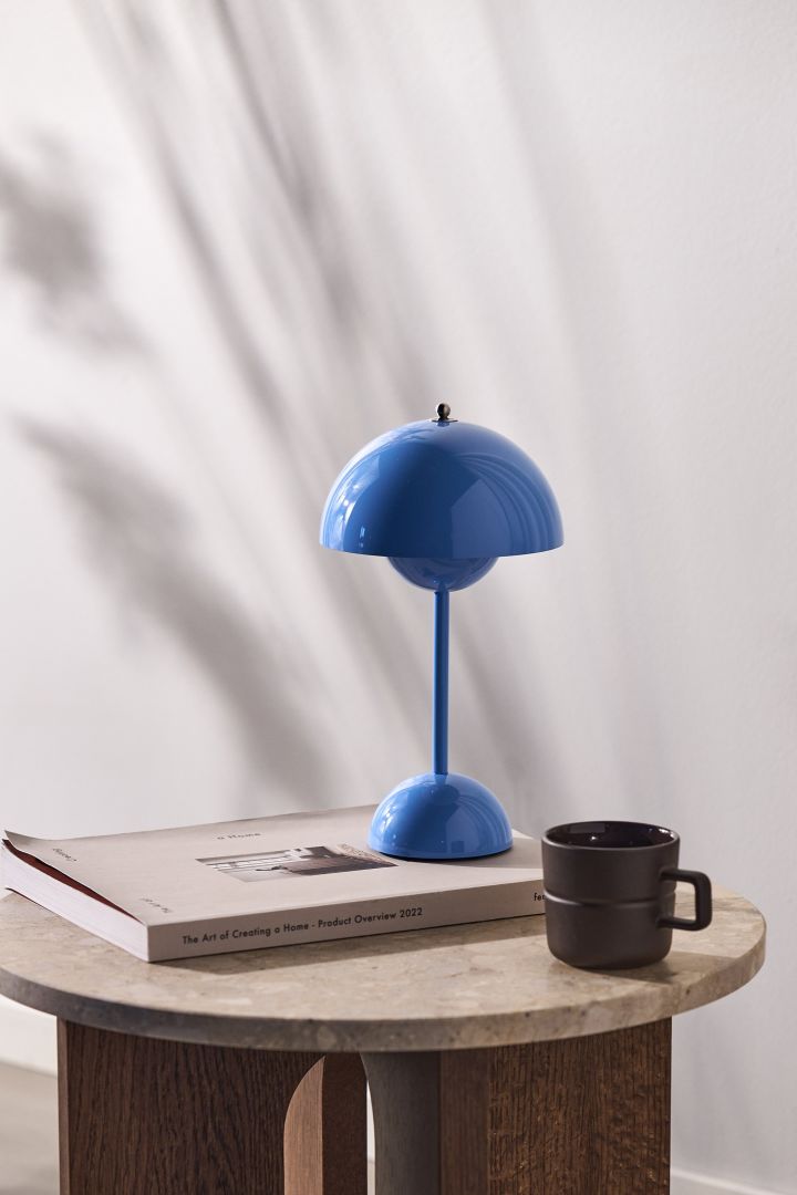 Flowerpot bærbar bordlampe VP9 i klar blå farge står på et sidebord i tre mot en naturlig hvit vegg.