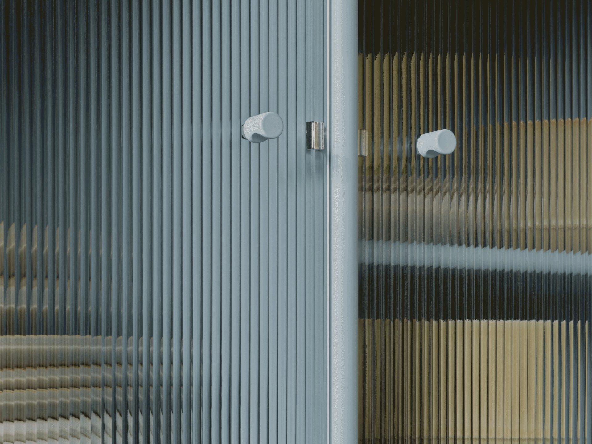 Nærbilde av riflet glassdør med to lyse runde håndtak, viser forvrengte farger gjennom den gjennomskinnelige teksturen.