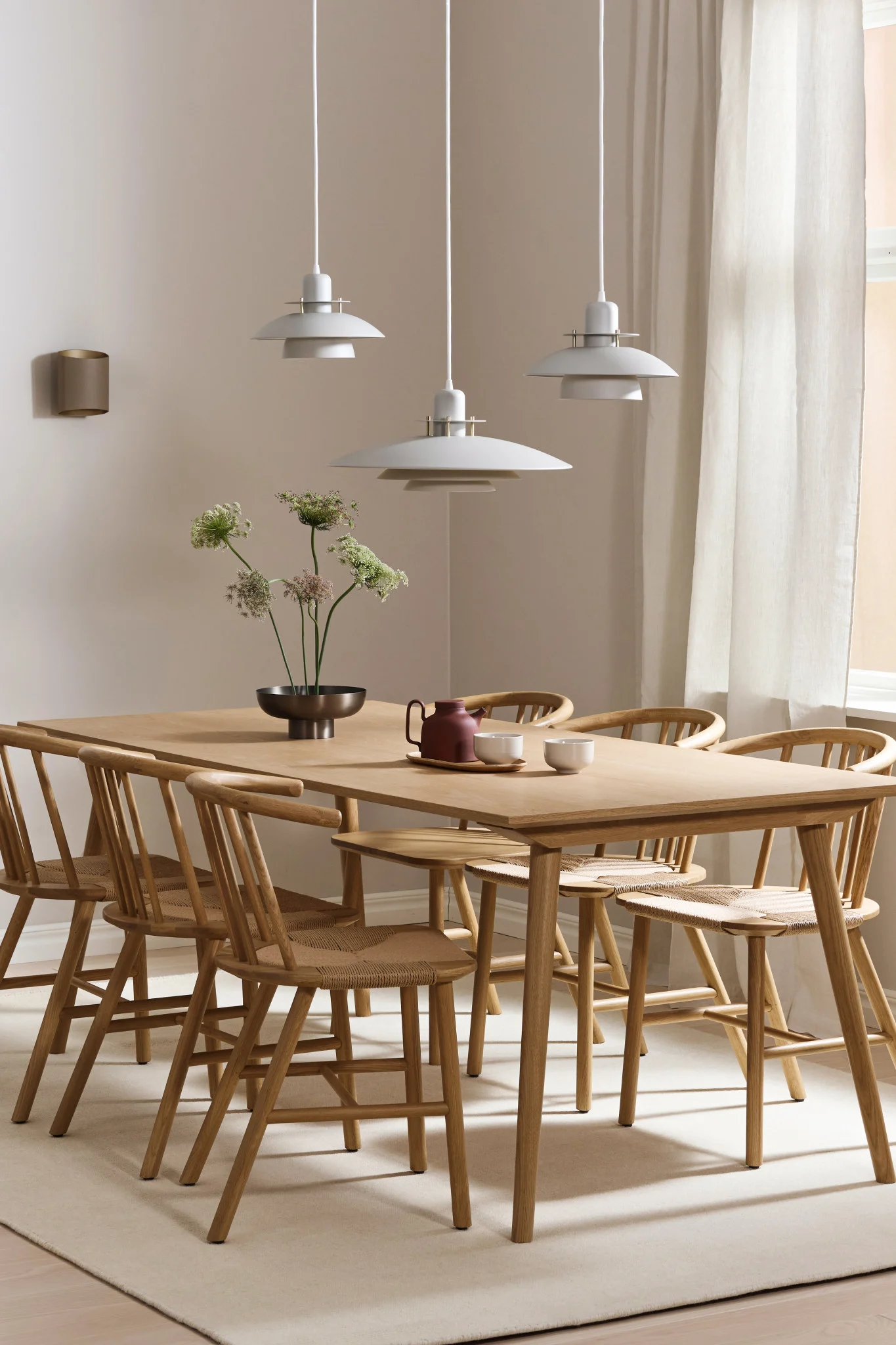 Her ser du belysningstips for et langt spisebord. Picasso-lampen henger i en rekke på tre, og Sinne-lampen er plassert på veggen.