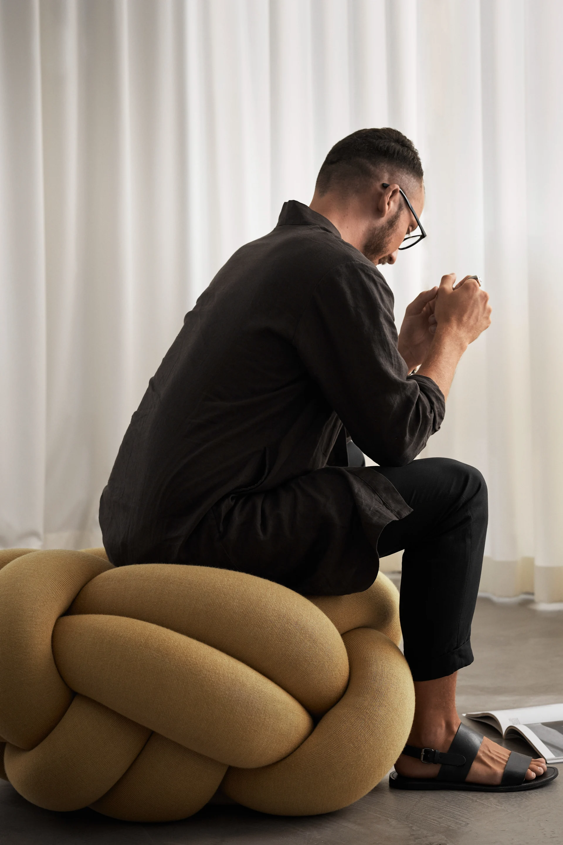 Mannen sitter på XL Knot pute i gult. 