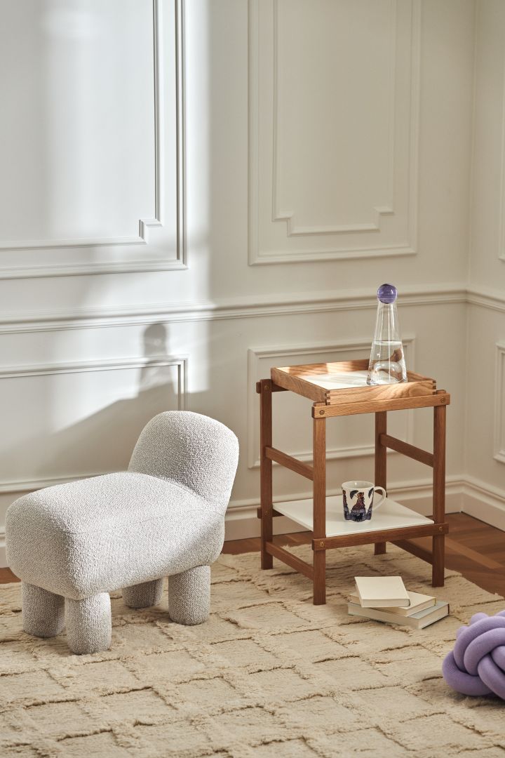 Stilren stue med produkter fra Design House Stockholm i form av Lulu-puff, Frame-hylle i eik, Knot-pute i lavendel og Elsa Beskow-krus.