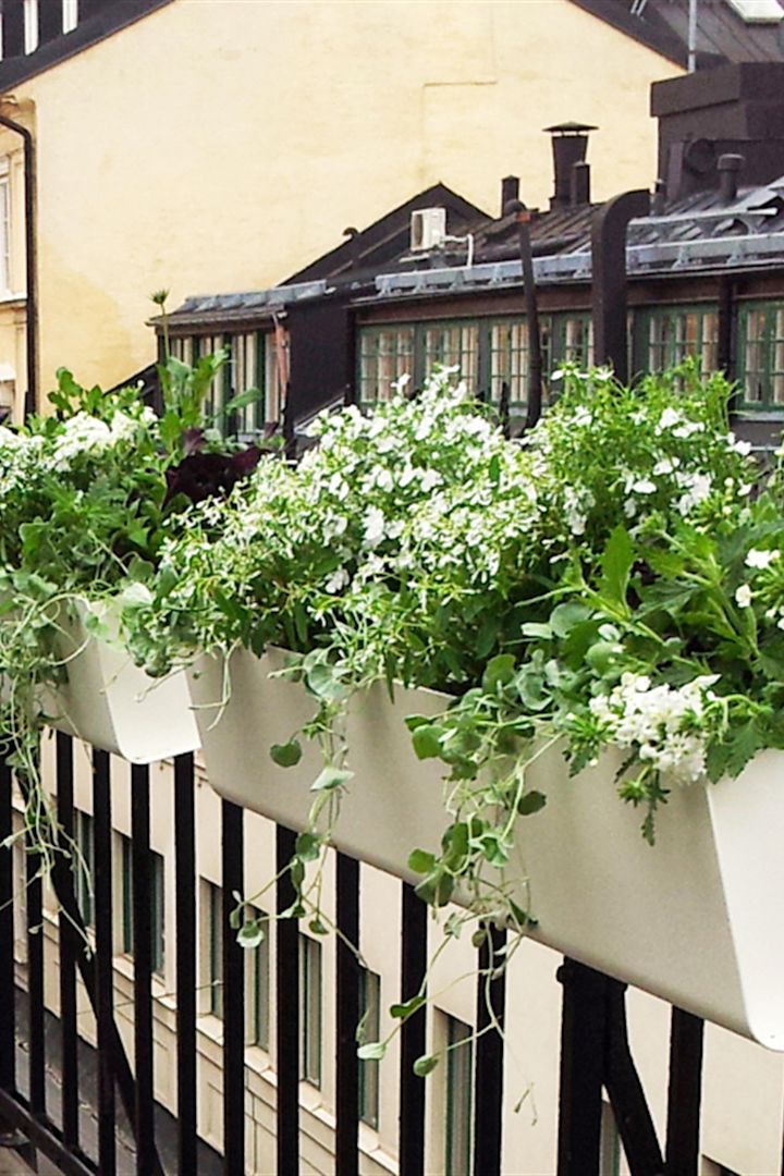 Blomsterkassen Jorda fra SDM Design henger på et balkongrekkverk.