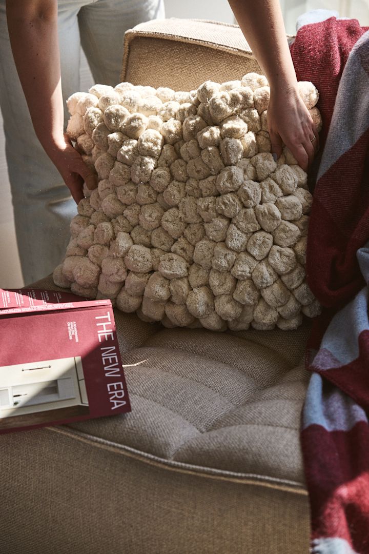Pom Pom-puten fra Byon, som her legges på en sofa sammen med et burgunder- og blåfarget pledd, er et flott eksempel på sesongens trend. Teksturerte og strukturerte materialer er en av høstens store interiørtrender 2024.