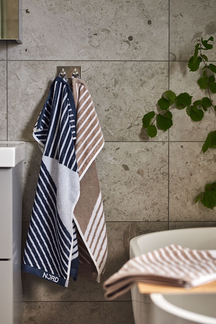 Lag et hjemmespa på badet ved å innrede med Stripes myke håndklær fra NJRD i beige og blått for avslappende stunder.