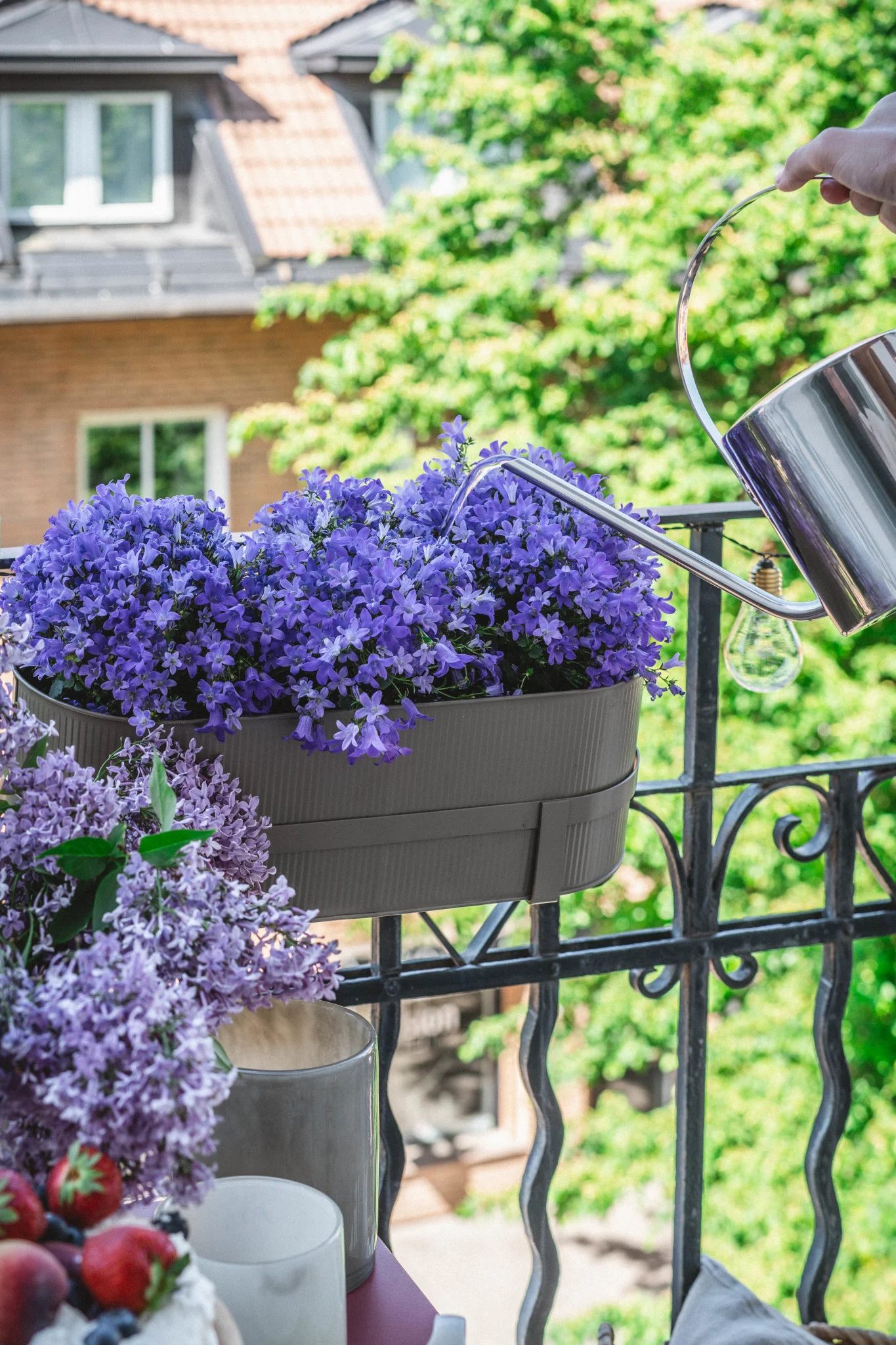Her ser du Bau blomsterpotte i beige fra Ferm Living på et balkongrekkverk.
