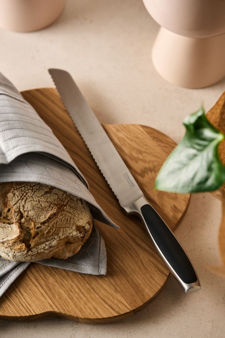 Kreative gaveideer til innflytting. Her ser du Royal brødkniv fra Fiskars på Alvar Aalto-brettet fra Iittala sammen med et grovt brød.