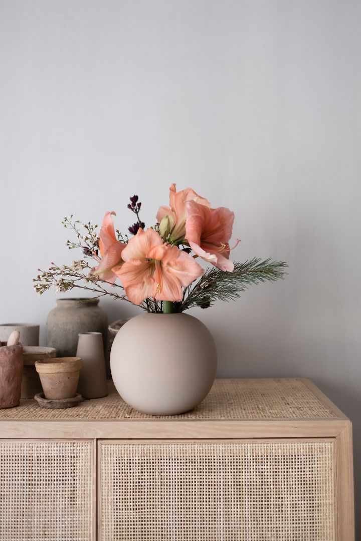 Stilleben interiør - her ser du en rund vase fra Cooee Design og aprikosfargede blomster på en kommode.