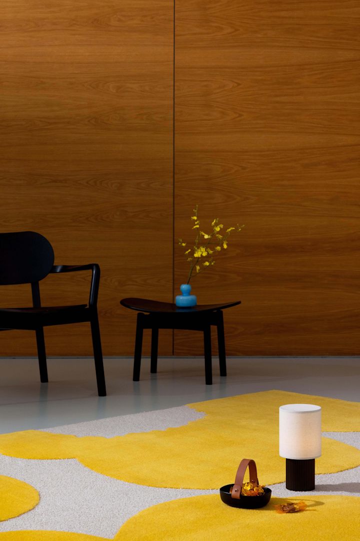 Den blå blomstervasen står på et gult og beige Unikko-teppe fra Marimekko.