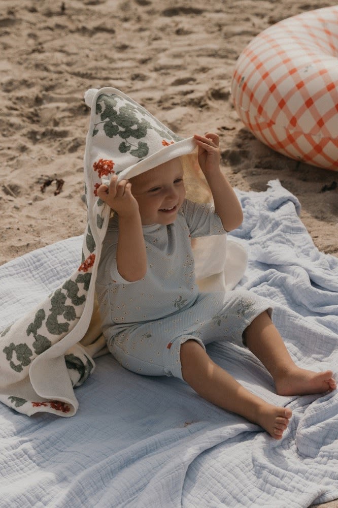 En baby ligger på et håndkle med hette i en matchende baby dress fra Garbo&Friends - perfekte gaveidéer til babyshower.