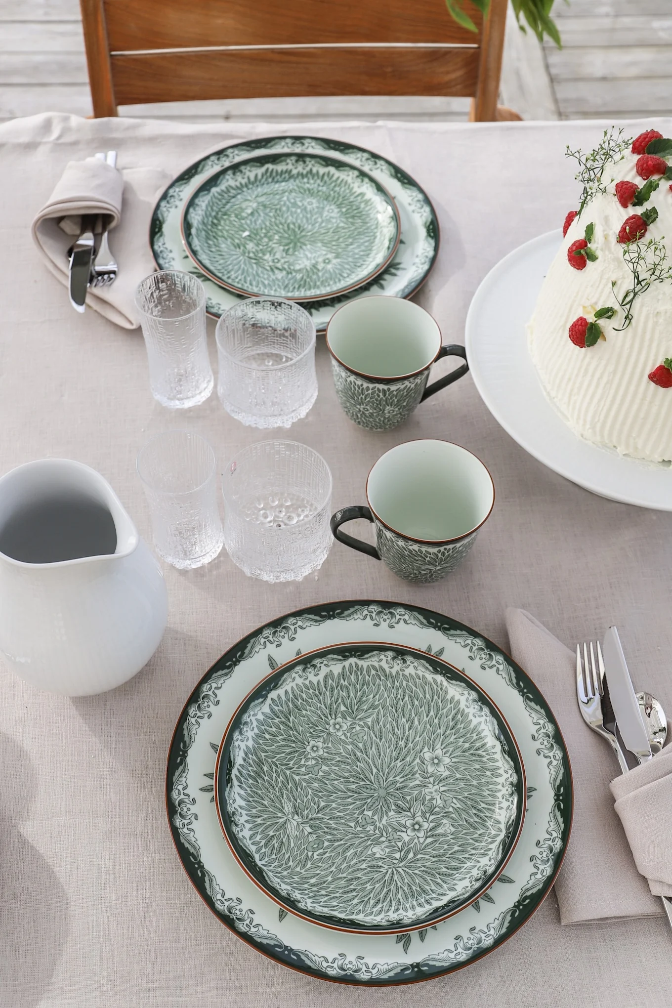 Tradisjonelle midtsommertips inkluderer selvfølgelig å spise ute i det fri. Her ser du det grønne serviset Ostindia og Ostindia Floris på bordet, sammen med Ultima Thule-glass fra Iittala.
