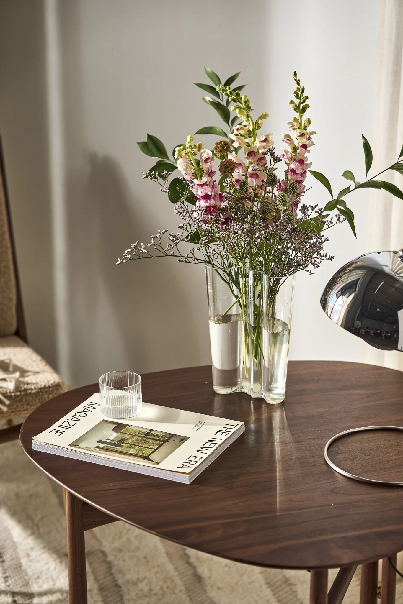 På et sidebord står den høye Alvar Aalto-vasen fra Iittala med friske blomster.