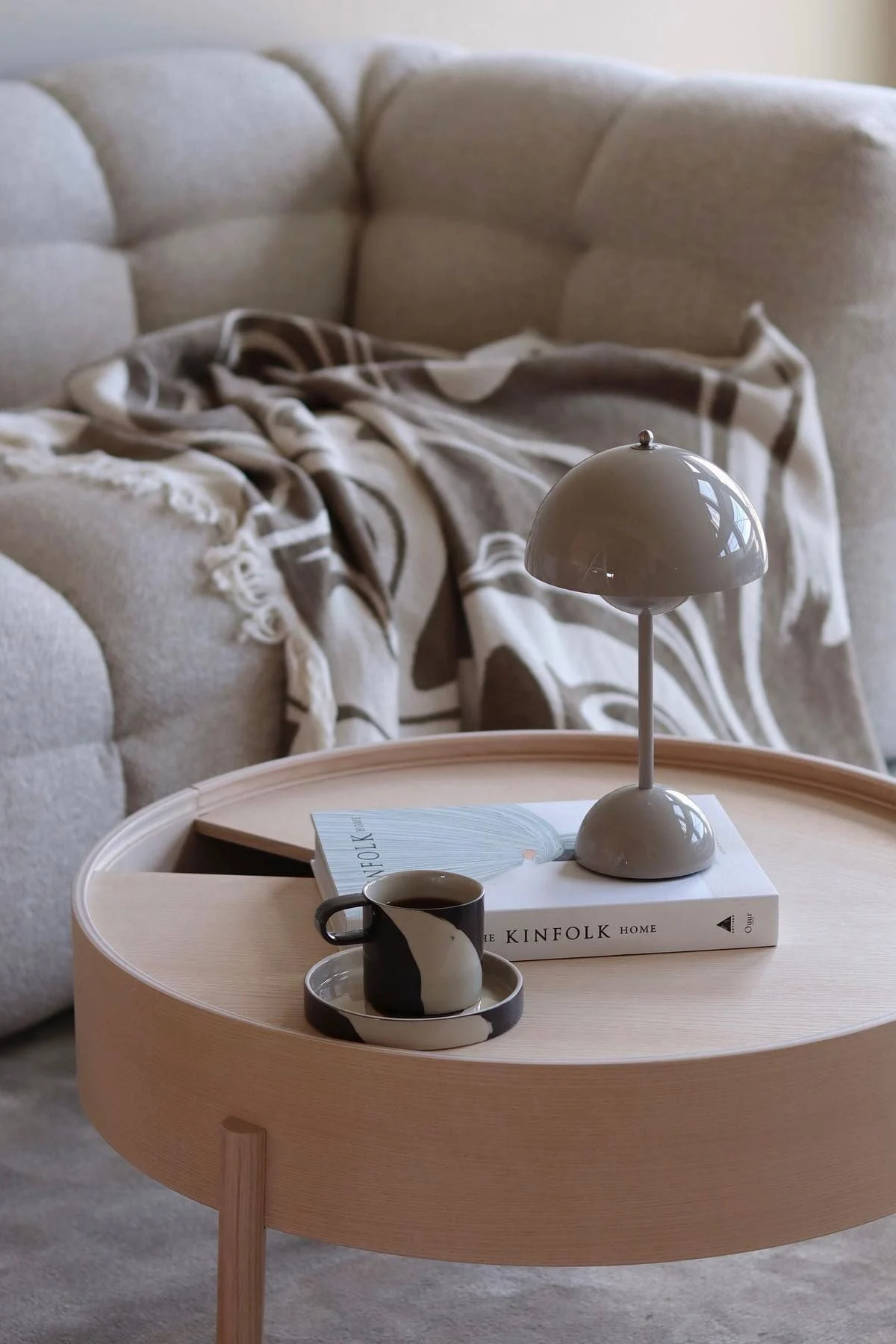 Et trebord er dekorert med en bok, en Flowerpot-bordlampe fra &Tradition og Inlay-koppen fra Ferm Living.
