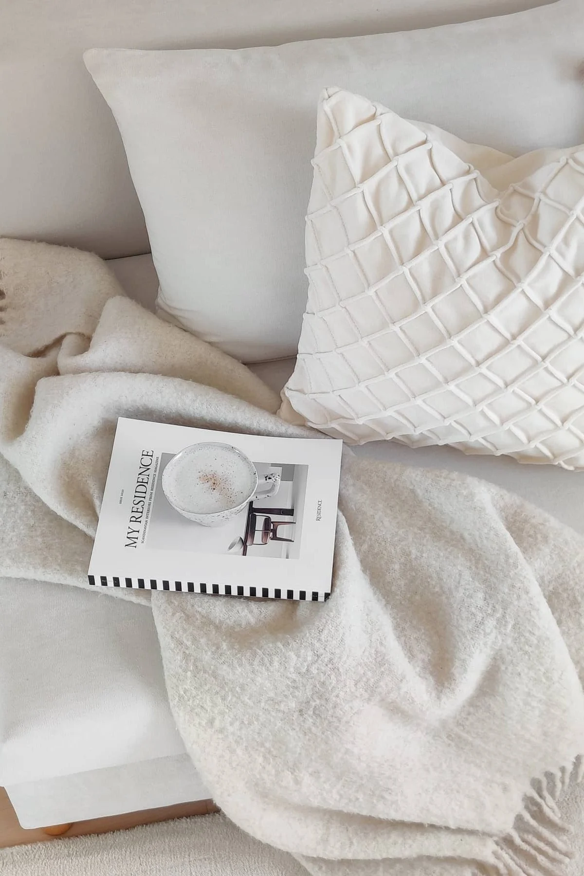 Valentinsdag gaver: På en hvit sofa ligger to hvite puter fra Chhatwal & Jonsson, Ralph-pleddet fra Klippan Yllefabrik, en bok og en kopp kaffe.