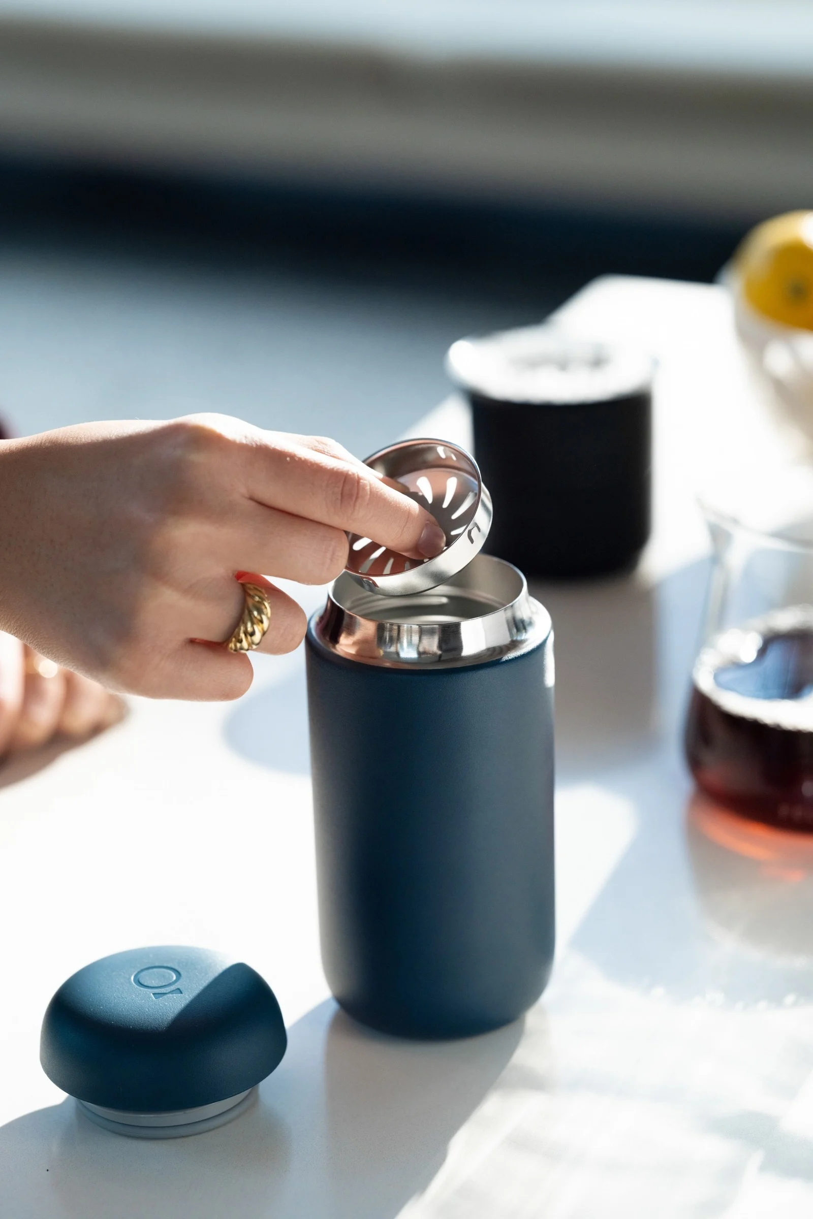 Ta enkelt med deg kaffen – med den blå Carter-termokoppen fra Fellow, vist her på et kjøkkenbord.
