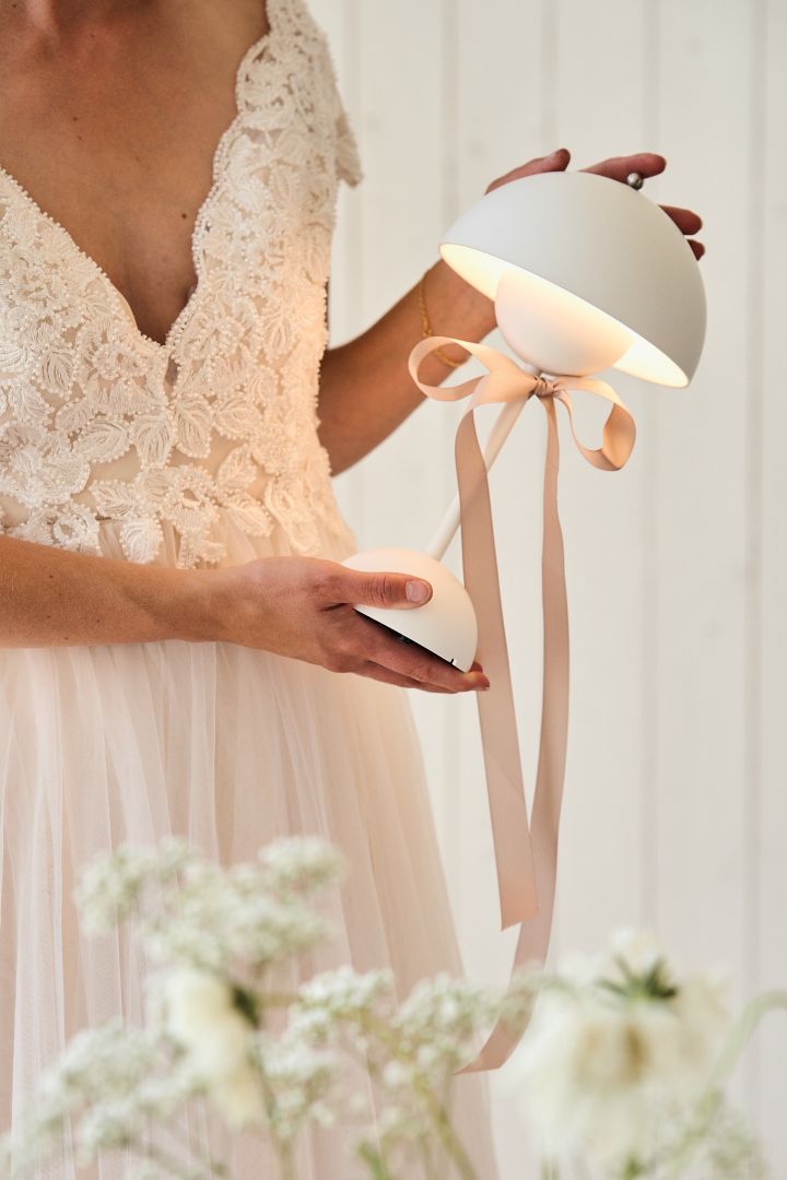 Her ser du en brud som holder en hvit VP9 Flowerpot bærbar bordlampe. Glem ikke gavebordet når du planlegger bryllupet ditt. 