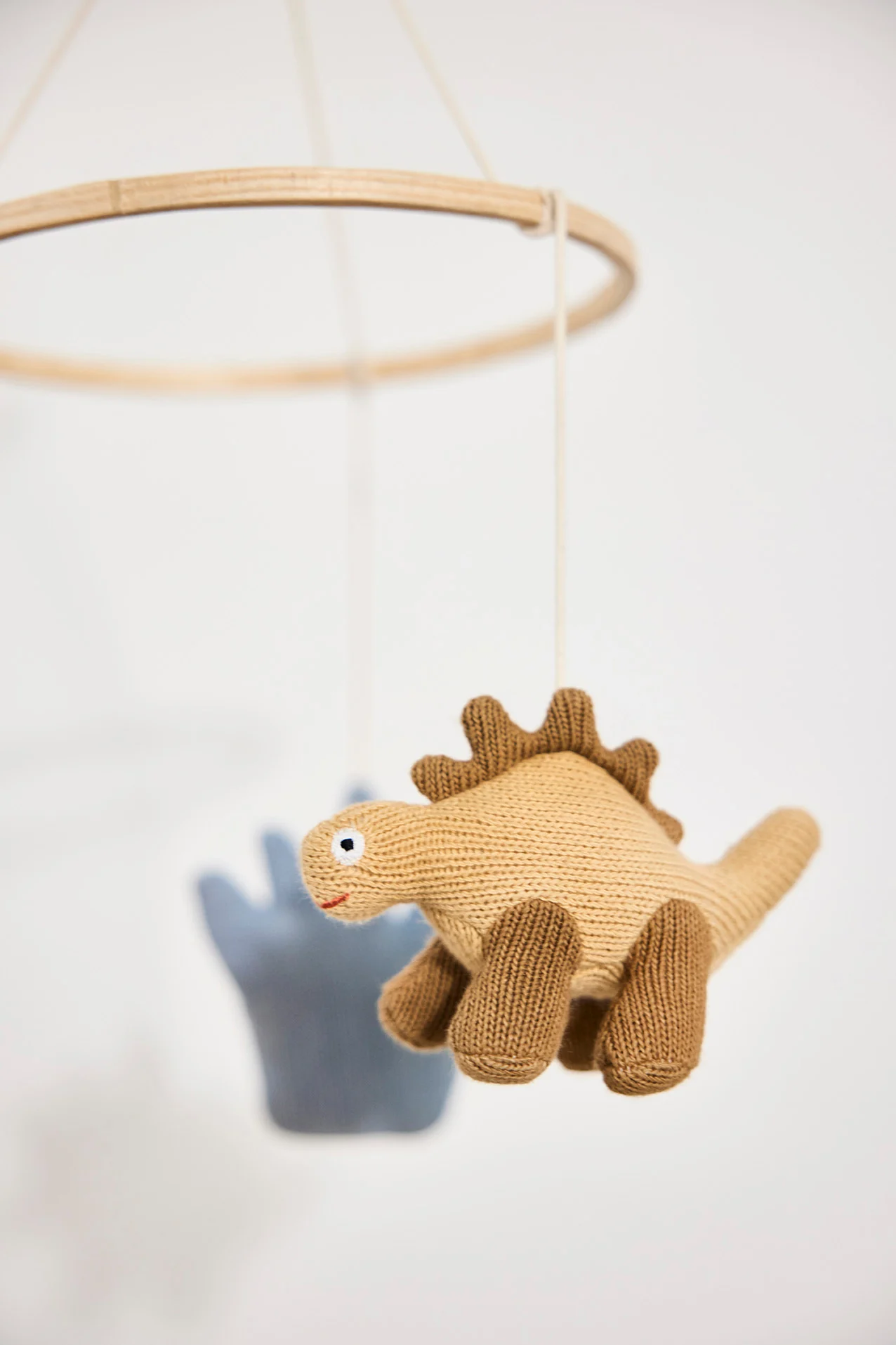 Et bilde av et babyrom med en mobil hengende over en sprinkelseng og et gulvgym på gulvet. Mobiler er perfekte gaveidéer til babyshower.