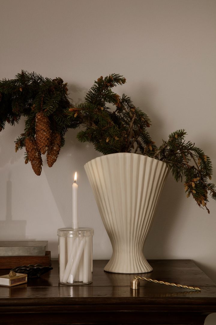 Kalenderlys i vakker krukke fra Ferm Living sammen med en høy, hvit vase for grankvister blir perfekt julepynt i 2022.