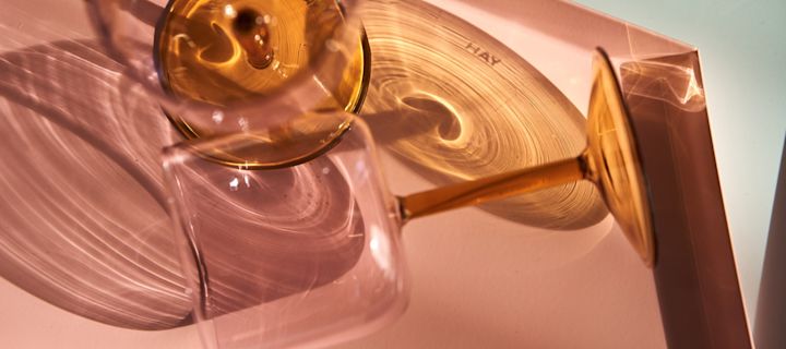 Nærbilde av fargerike Tint vinglass i gult og rosa på Kaleido brett i rosa fra HAY.