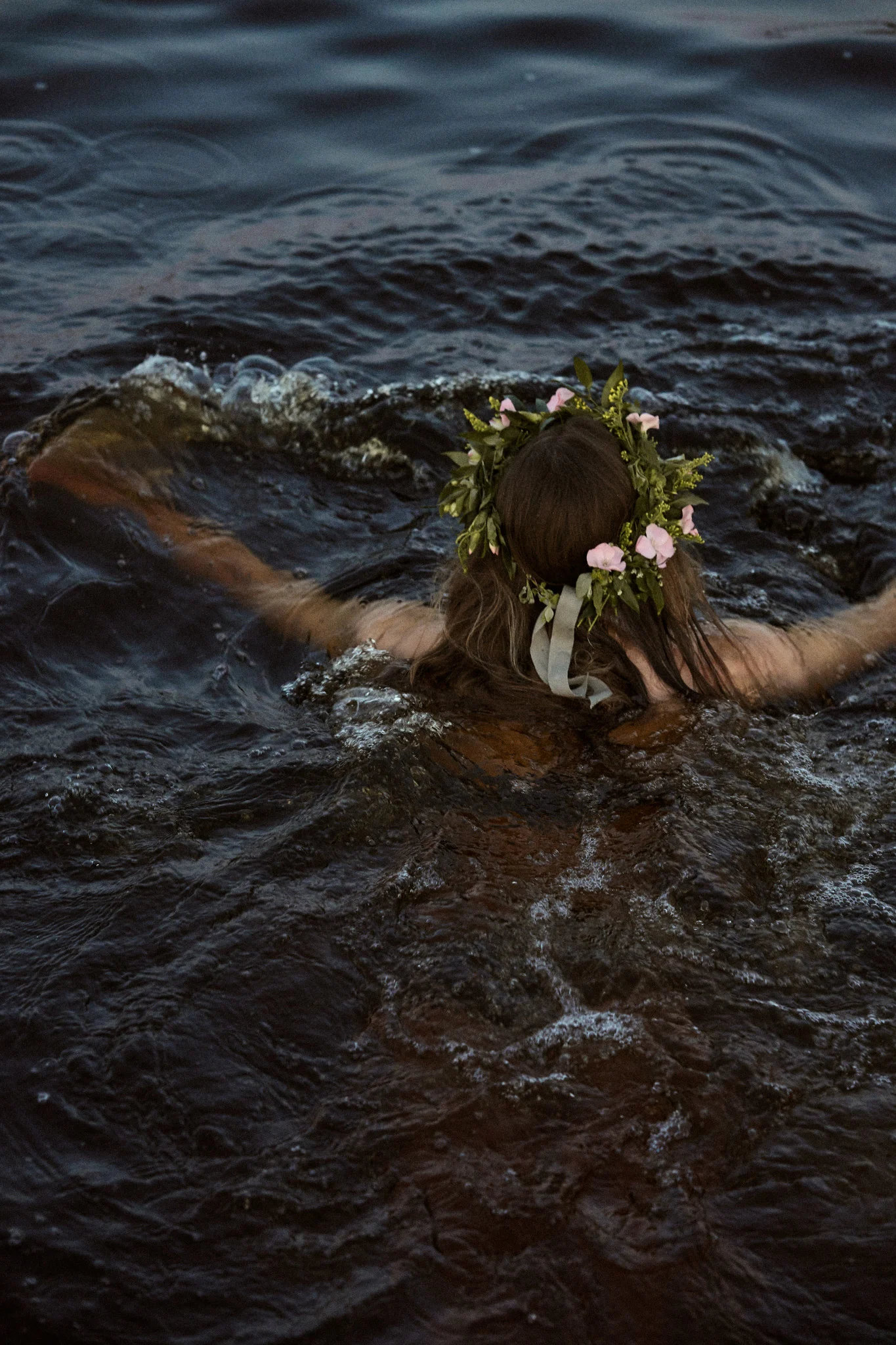 Midtsommer Orrefors - her ser du en kvinne med blomsterkrans på hodet som svømmer.