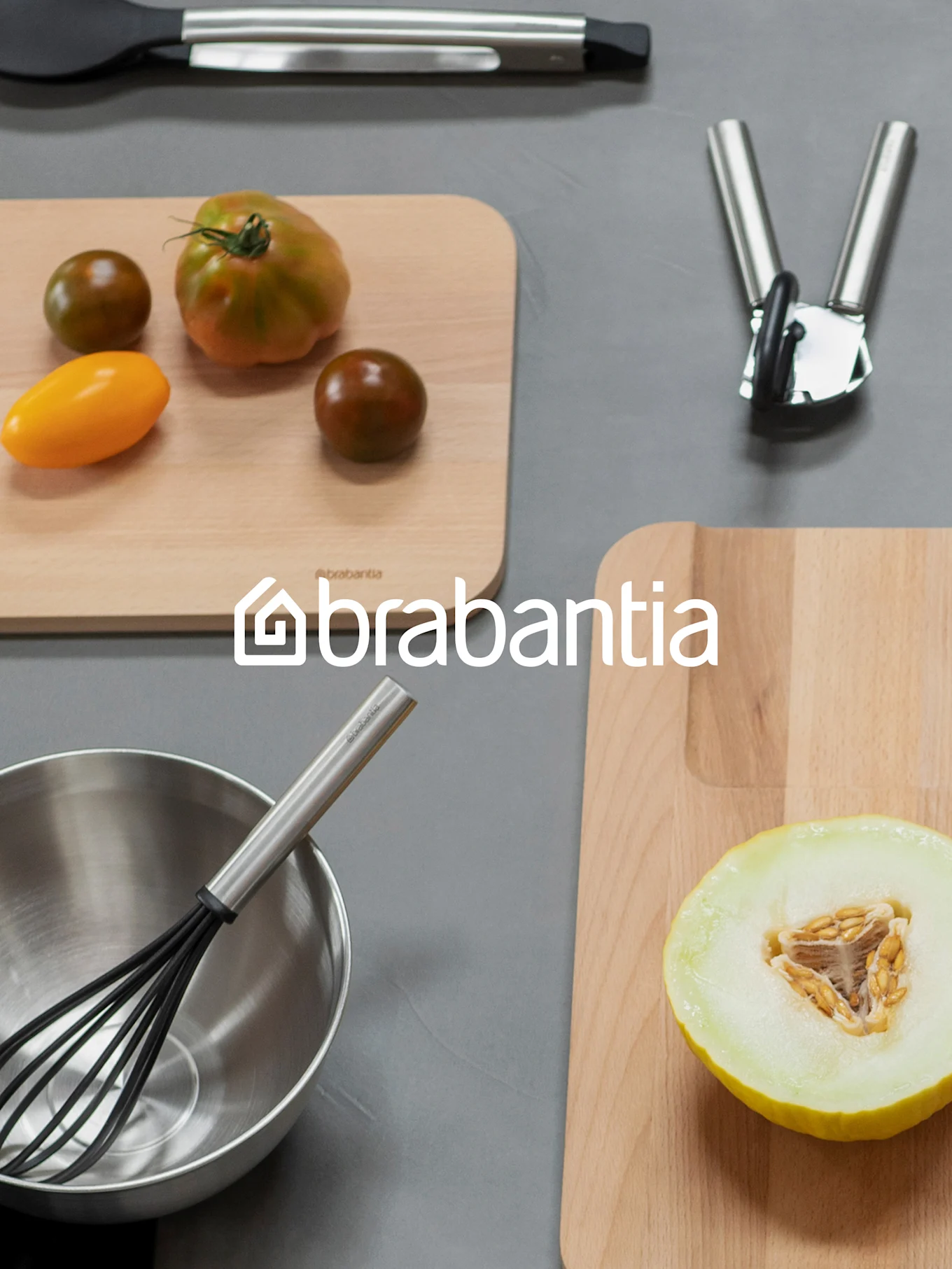 Brabantia-logo over et oversiktsbilde av kjøkkenutstyr inkludert skjærebrett med tomater og melon, en visp i en bolle, og andre redskaper.