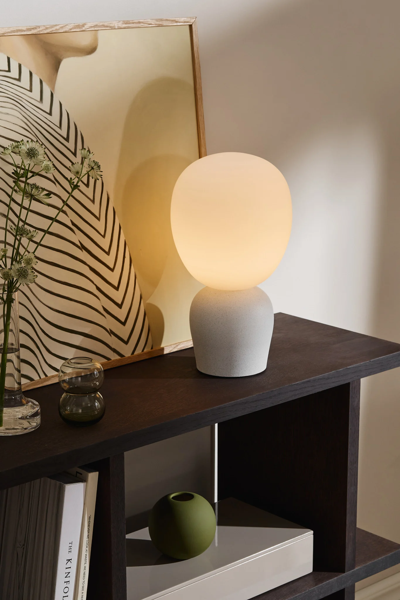 Bruk ulike lamper – som bordlamper, vegglamper og taklamper – for å lyse opp spisestuen på en balansert og stilfull måte. Her ser du Buddy bordlampe fra Belid med frostet glasskjerm.