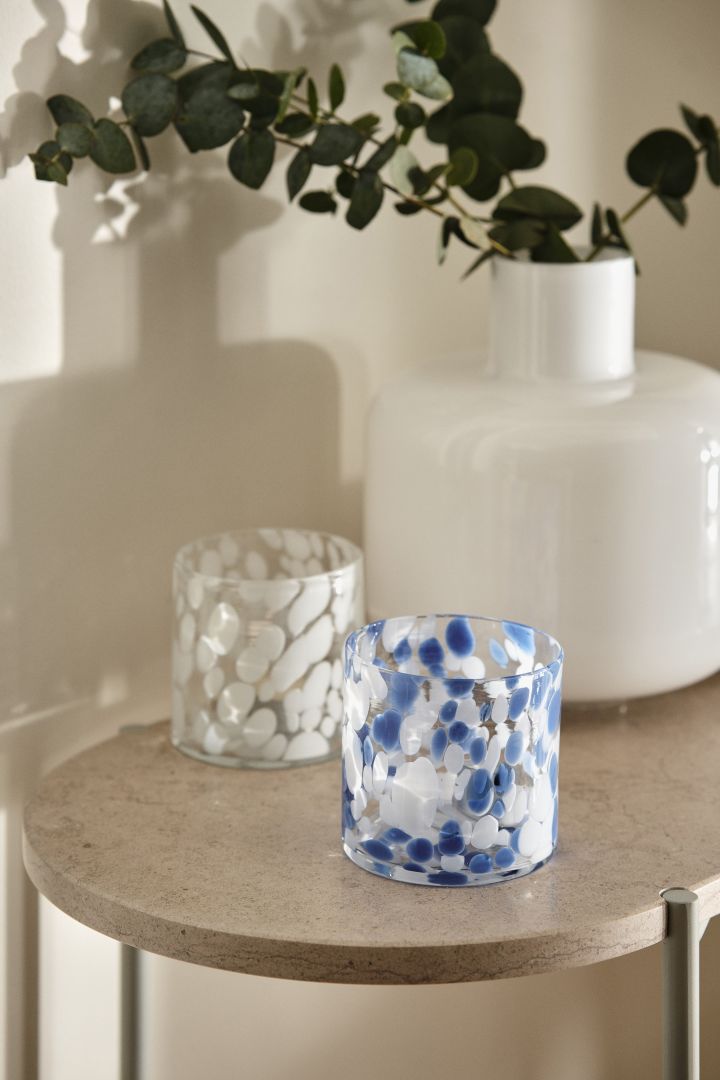 Cloud fra Scandi Living i blått og hvitt med et mønster som minner om skydannelse står på et sidebord i marmor mot en naturlig hvit vegg.