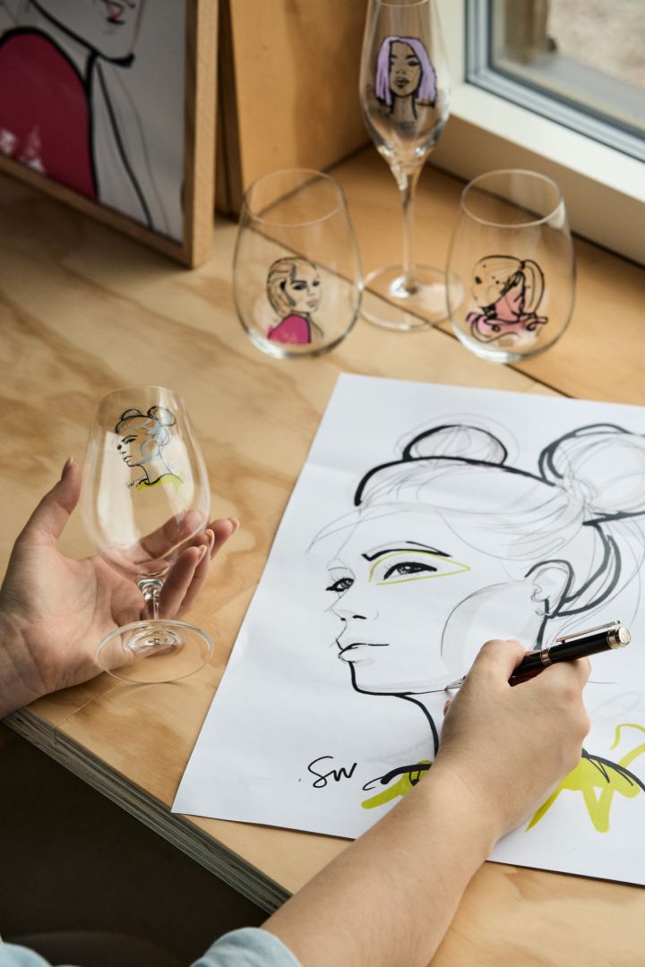 En person holder et ølglass fra All About You -serien i den ene hånden og lager en skisse med den andre.