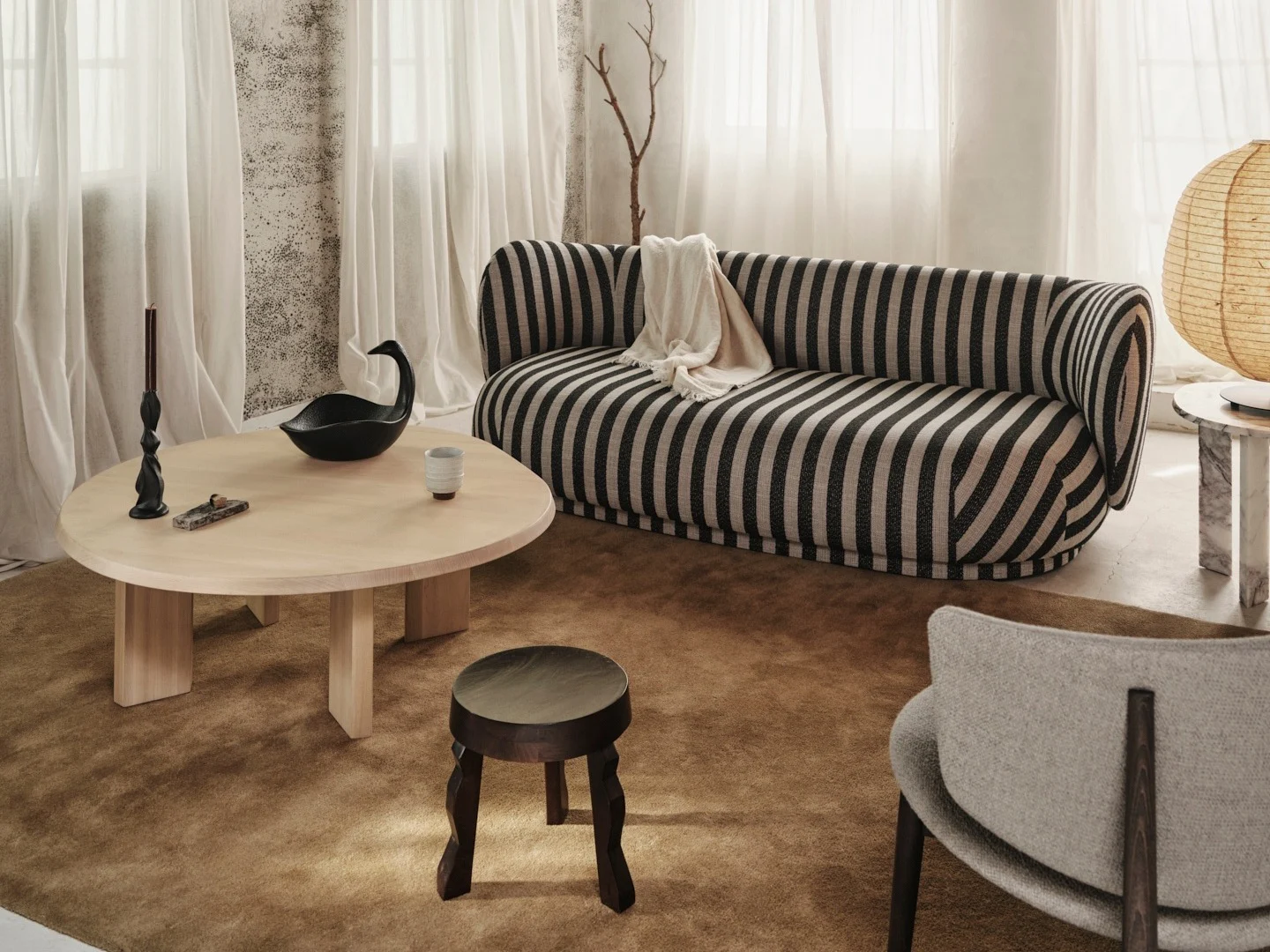 Koselig stue med en svart og off-white stripete sofa, lyst salongbord i tre og rustikt bjelketak i tre.