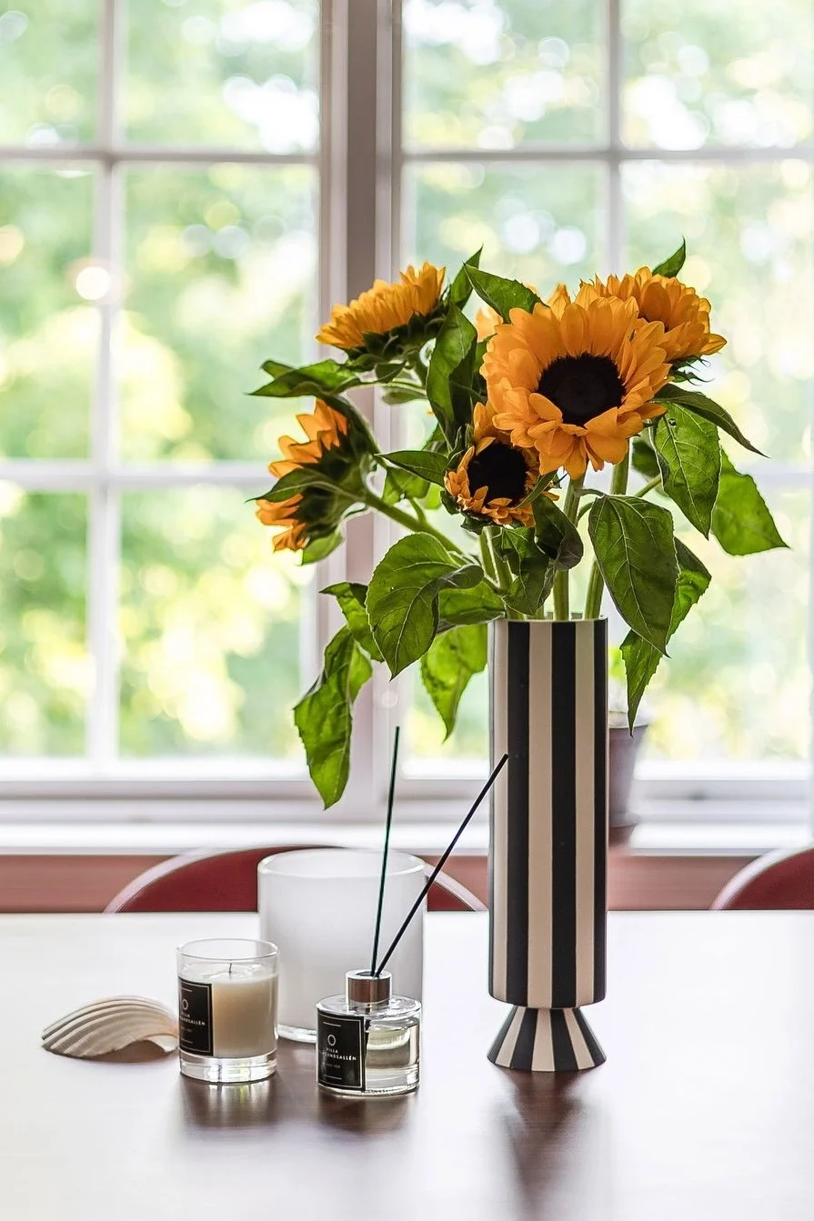 Den beste vasen for blomster med lange stilker – her ser du en høy vase med svarte og hvite striper, fylt med solsikker.