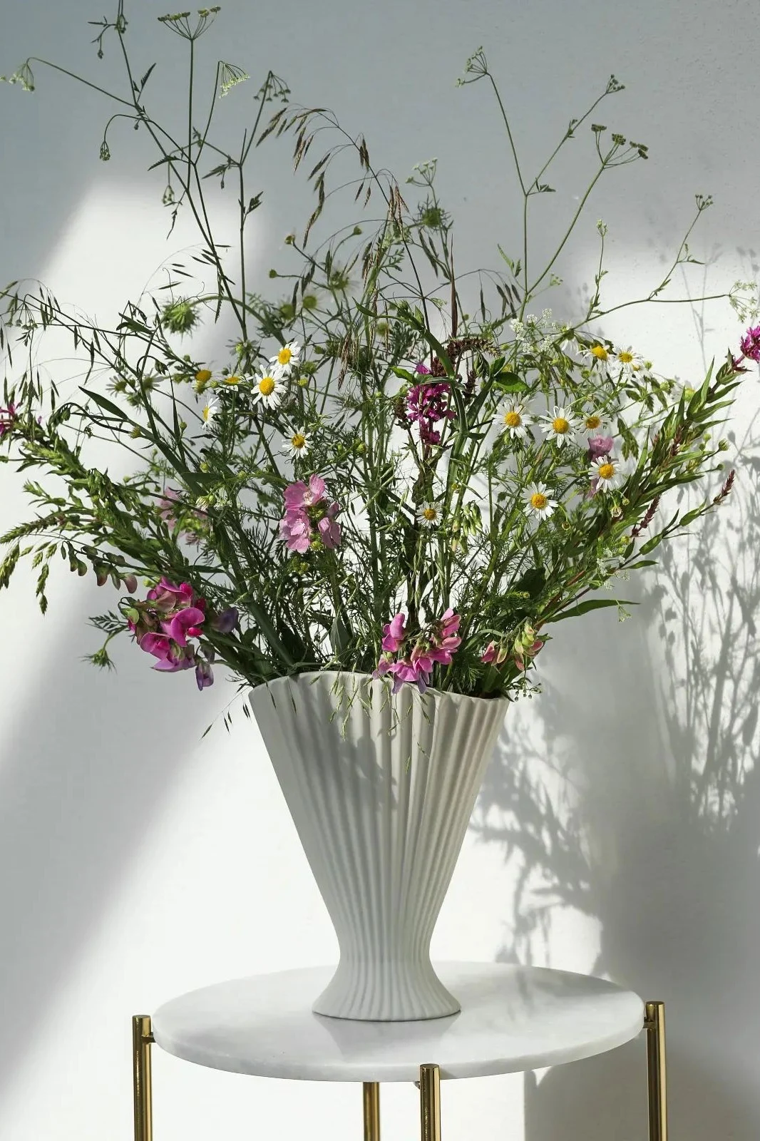 Den beste vasen for blomster med lange stilker – her ser du en høy vase med svarte og hvite striper, fylt med solsikker.