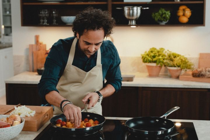Kokken Markus Aujalay lager mat på kjøkkenet sitt med stekepanner fra sitt eget merke med matlagingsprodukter i et med Nordic Nest.