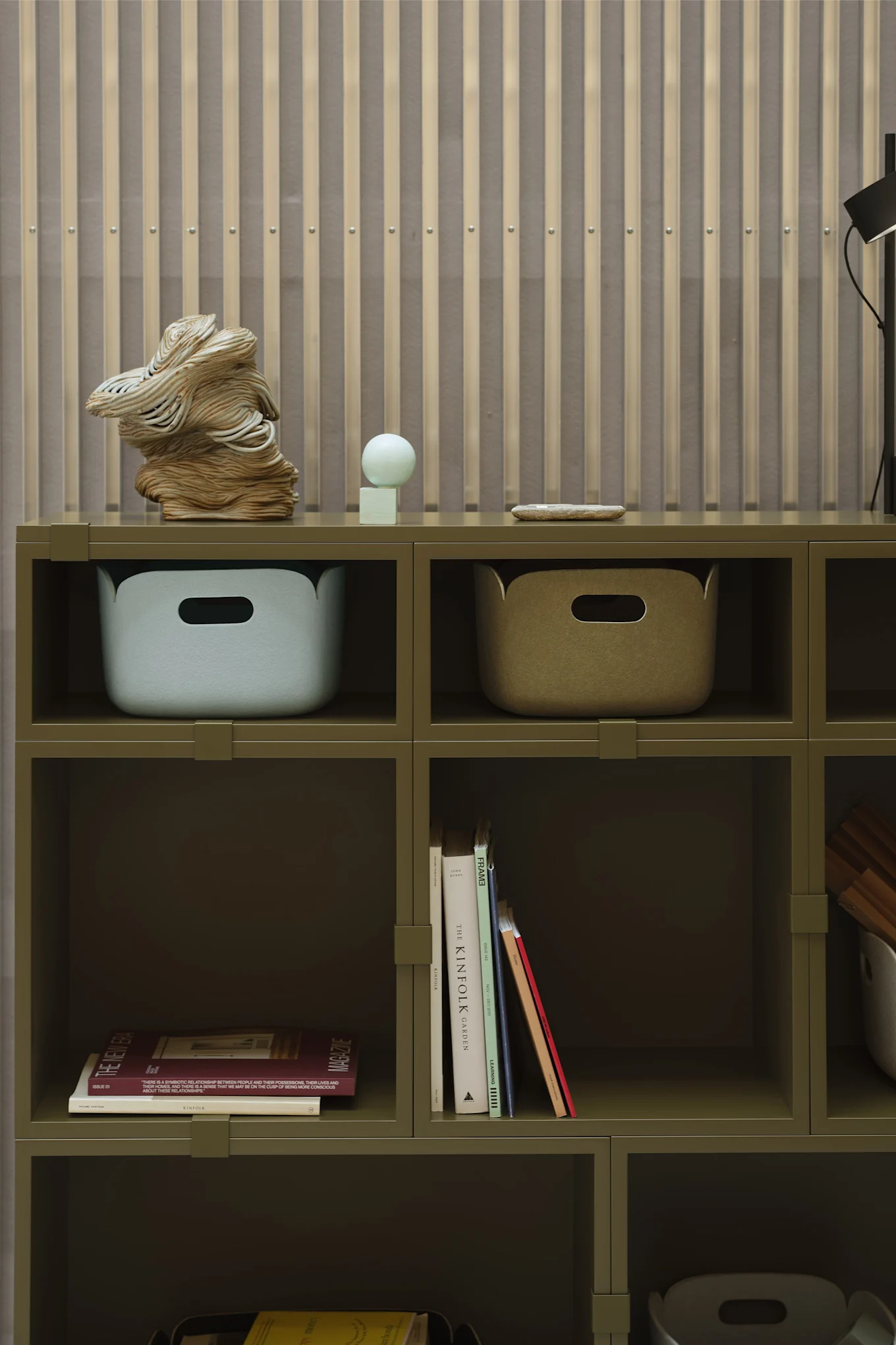 En grønn hylle med oppbevaringsbokser og bøker som detaljer, i tråd med interiørtrender 2026.
