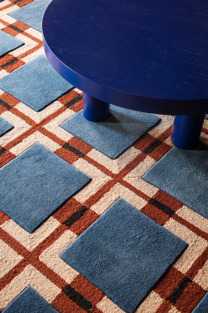 Kombinasjonen av farge og mønster på tekstiler og tepper er stor i interiørtrender i 2024, her i rødt/blått ullteppe med geometrisk mønster fra Layered.