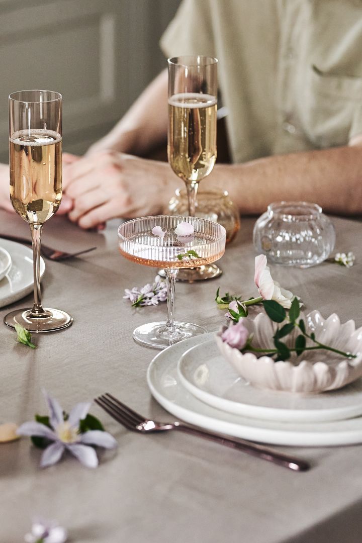 Dekk bordet til en romantisk middag hjemme på Valentinsdagen, nyt vin i fine glass og server på fint servise.