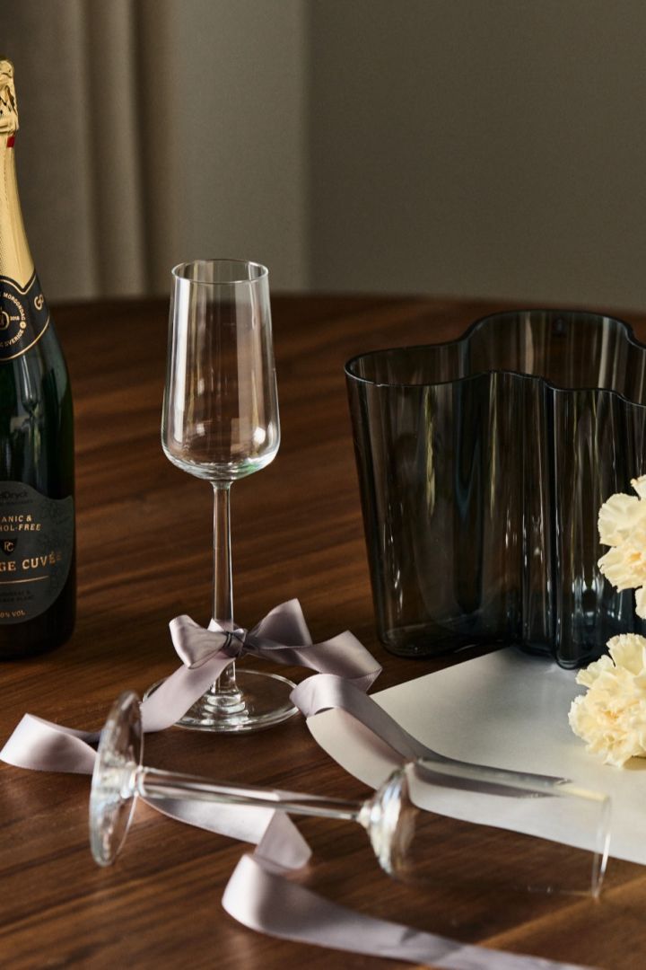 Kreative gaveideer til forlovelsesfesten. Her ser du Essence champagneglass fra Iittala med en flaske champagne og akkompagnert av Alvar Aalto-vasen.